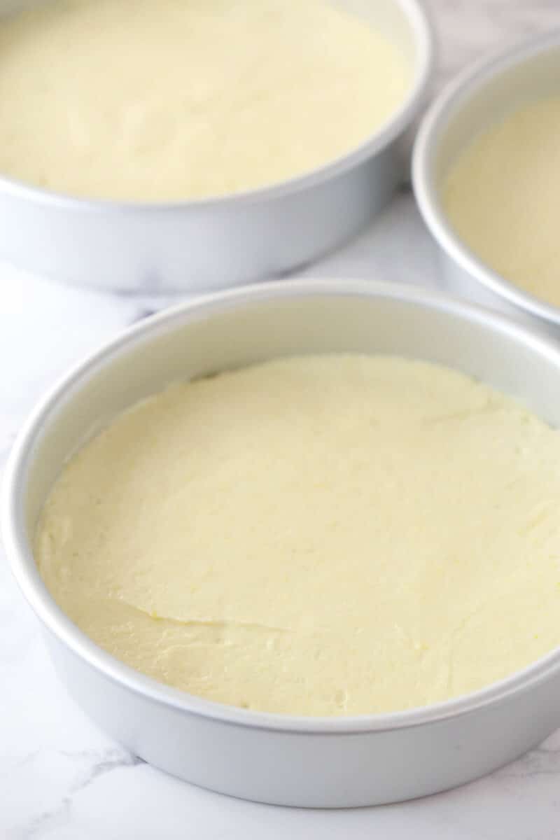 Lemon cake batter divided into three cake pans.