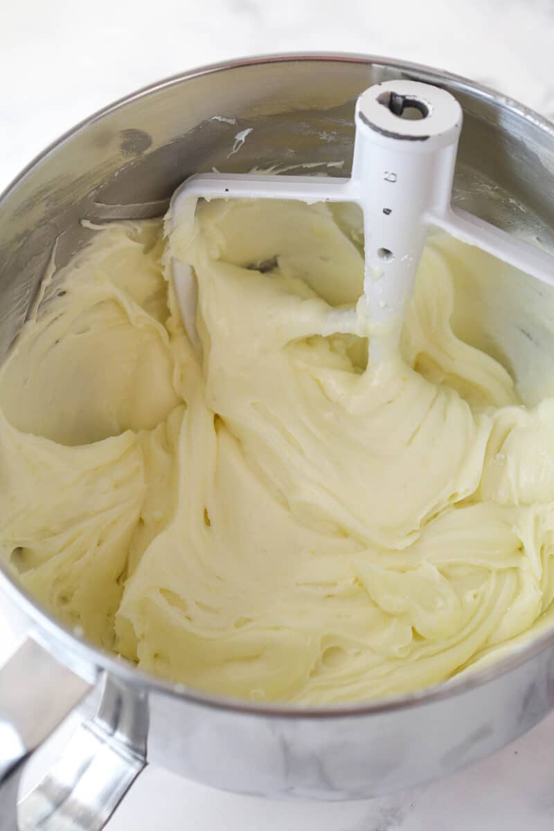 This lemon layer cake is made up of three layers of fluffy lemon cake that are filled and frosted with vibrant lemon cream cheese frosting. Lemon cream cheese frosting in a mixing bowl.