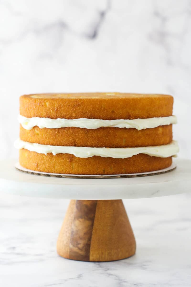 Three layers of lemon cake stacked on top of each other with cream cheese frosting between each layer.