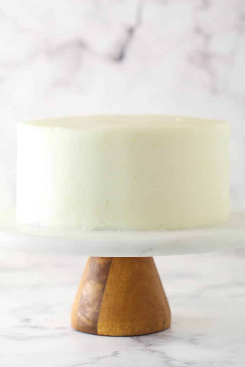 A smoothly frosted layer cake on a cake stand.