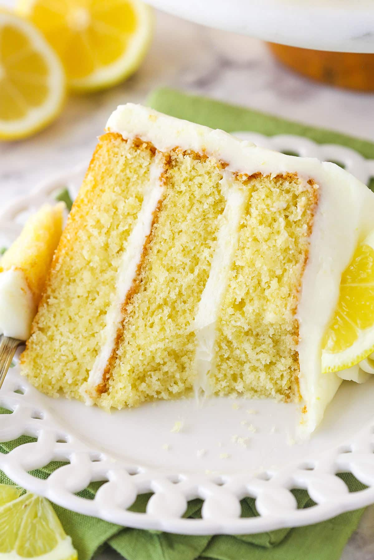 Lemon layer cake on a plate with a bight taken out of it.