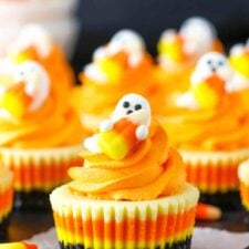 A Mini Candy Corn Cheesecake on a black table top surrounded by candy corn