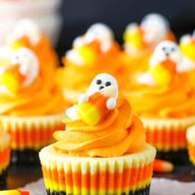 A Mini Candy Corn Cheesecake on a black table top surrounded by candy corn