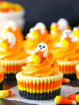 A Mini Candy Corn Cheesecake on a black table top surrounded by candy corn