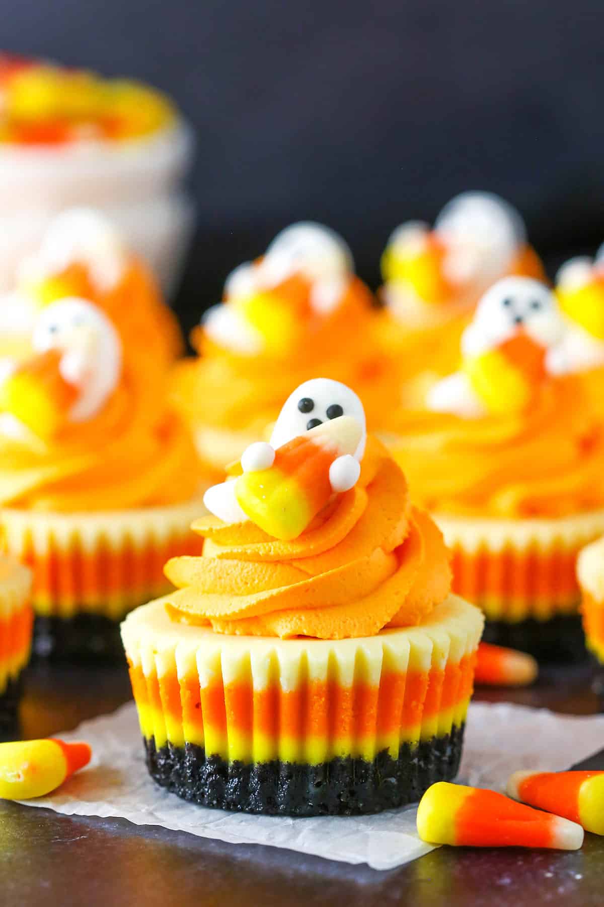 A Mini Candy Corn Cheesecake on a black table top surrounded by candy corn