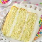 A slice of moist vanilla layer cake on a plate with a fork.