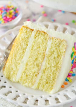 A slice of moist vanilla layer cake on a plate with a fork.