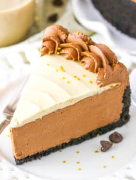 A slice of No Bake Baileys Chocolate Cheesecake next to a fork on a white plate