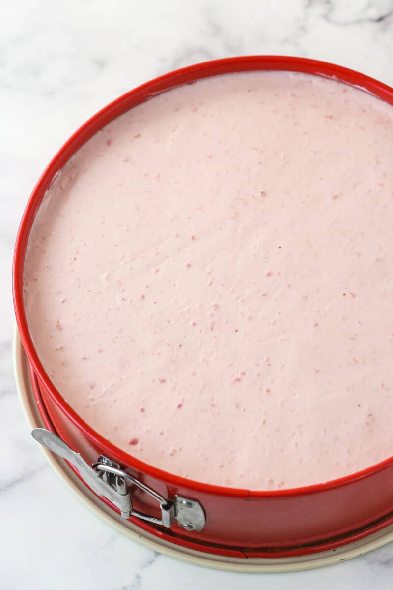 Undecorated no bake strawberry cheesecake in a springform pan.