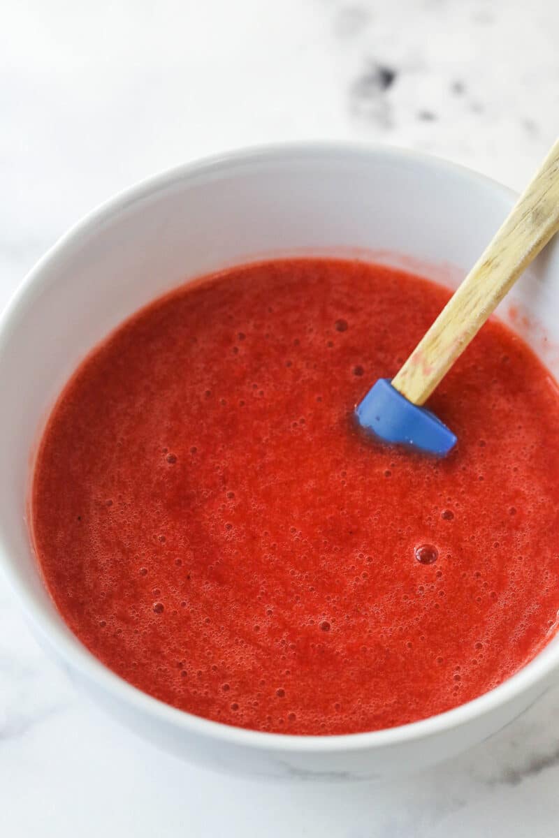 Strawberry puree in a bowl with a rubber spatula.