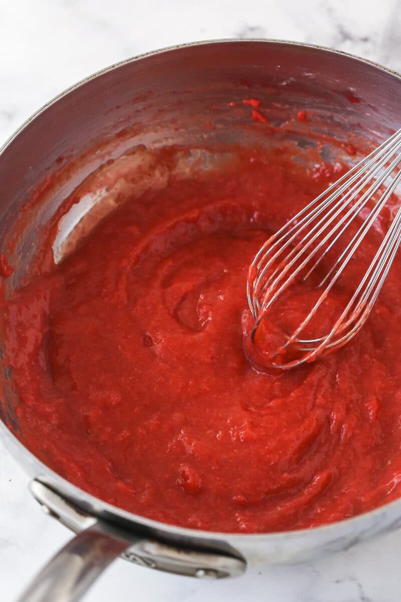 Whisking thickened strawberry mixture for no bake strawberry cheesecake filling.