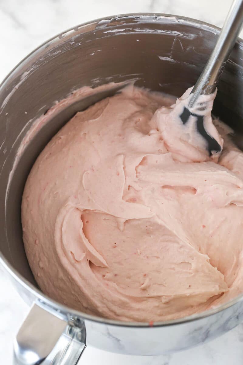 Folding whipped cream into cream cheese and strawberry mixture for no bake cheesecake filling.
