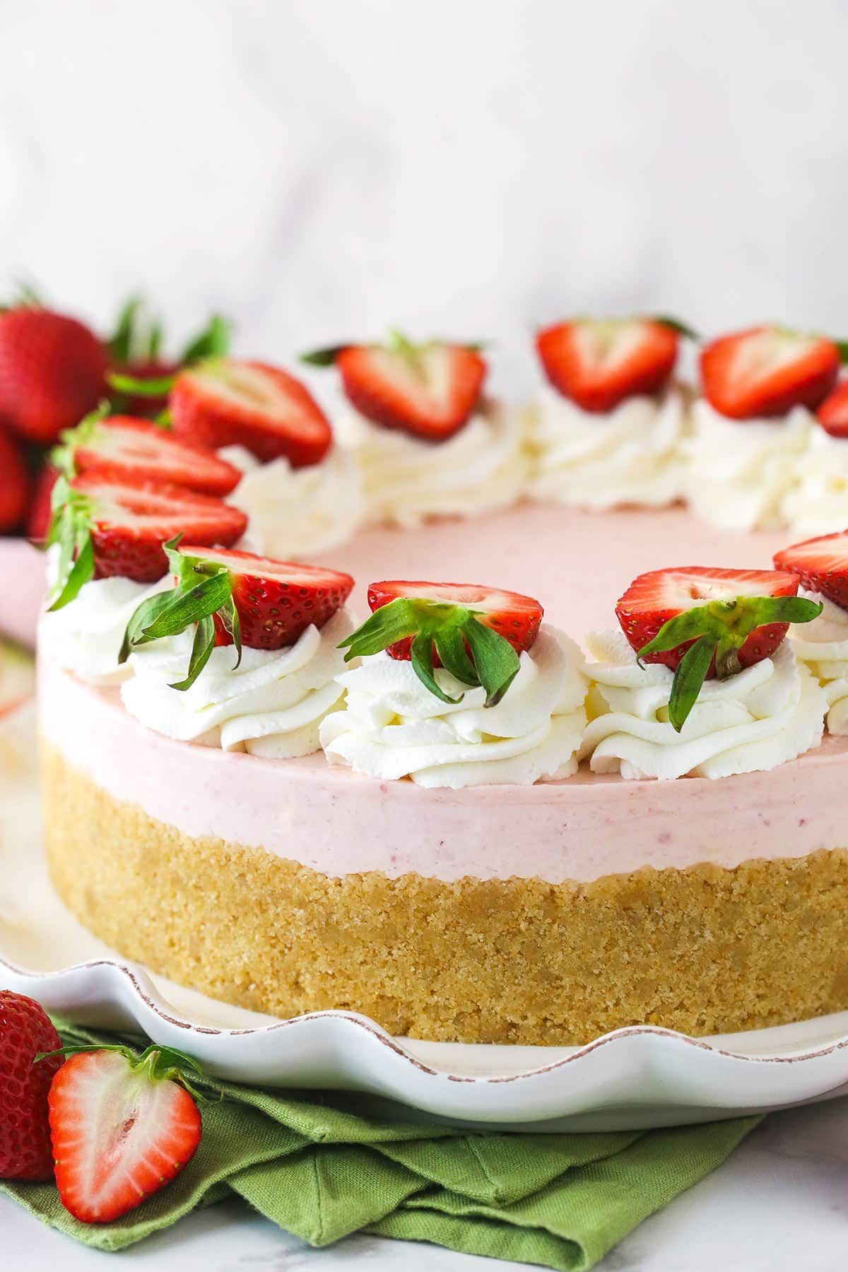 No bake strawberry cheesecake on a serving platter near fresh strawberries.