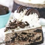 A slice of Oreo Cheesecake next to a fork on a white plate