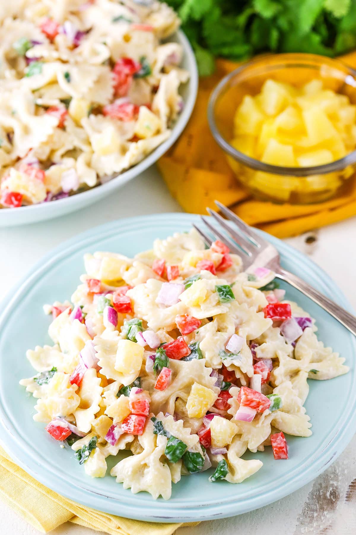 A serving of Pineapple Salsa Pasta Salad next to a fork on a light blue plate