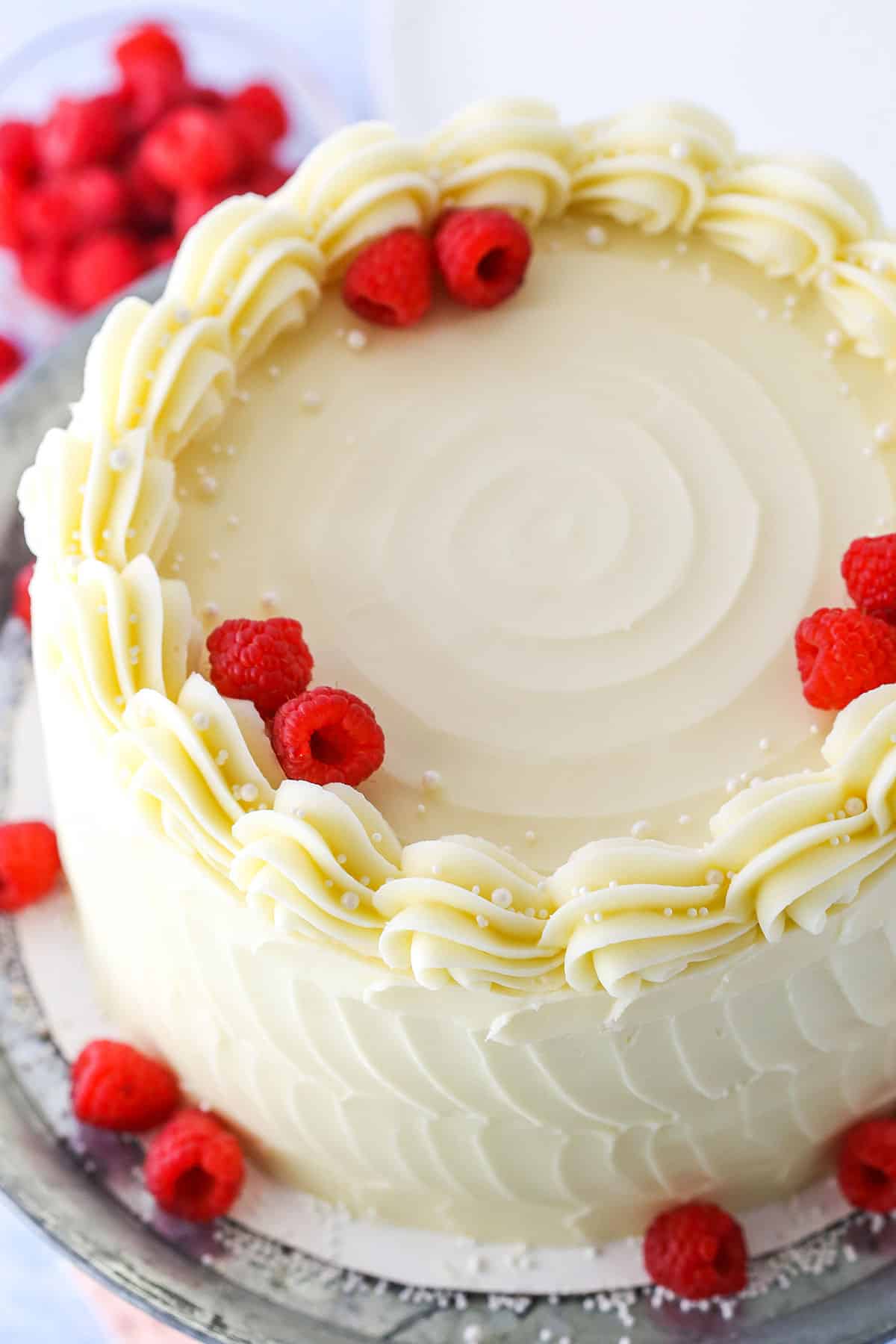 Overhead view of a full Raspberry Dream Cake topped with whole raspberries