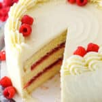 A Raspberry Dream Cake with a slice removed on a silver cake stand