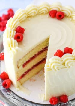 A Raspberry Dream Cake with a slice removed on a silver cake stand