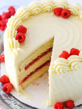 A Raspberry Dream Cake with a slice removed on a silver cake stand