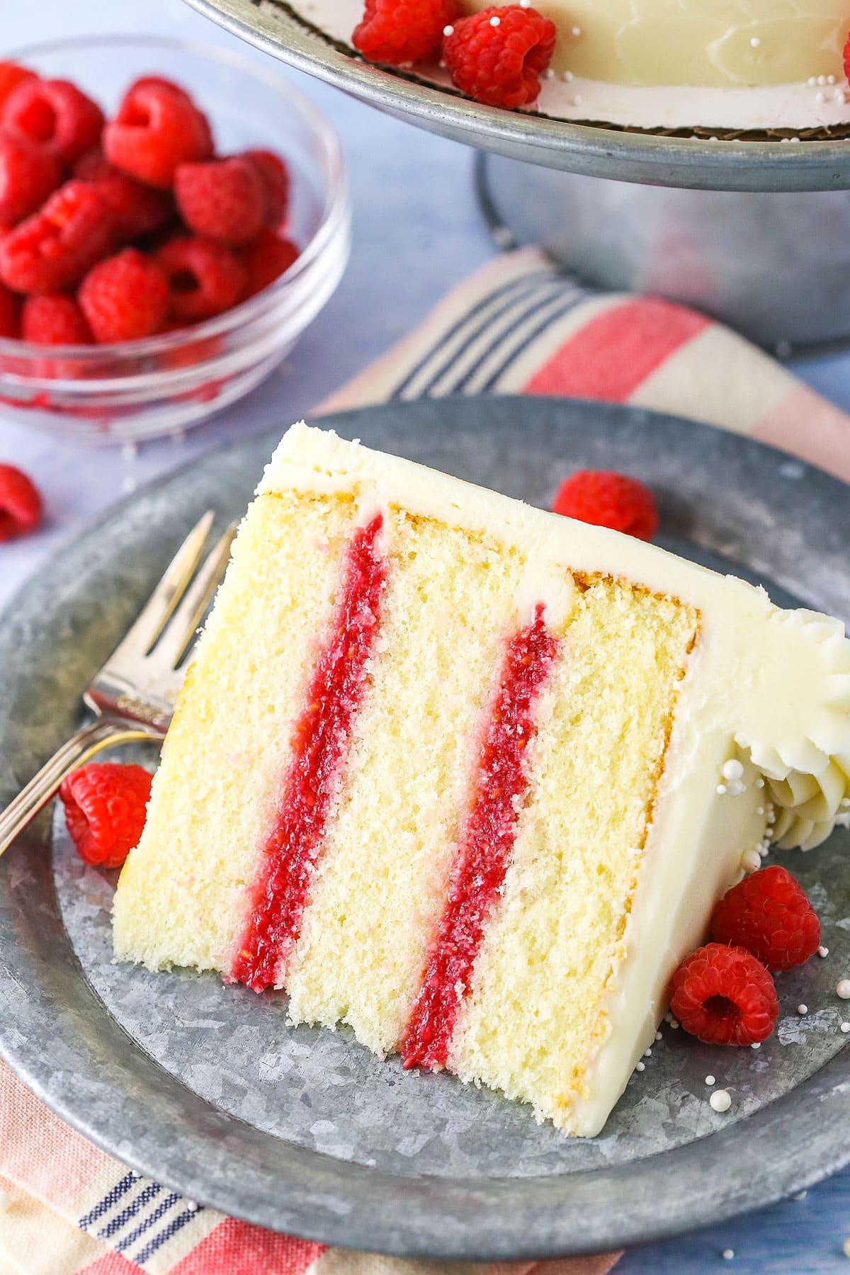 A slice of Raspberry Dream Cake on it's side next to a fork on a grey plate