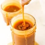 Overhead of dripping Salted Caramel Sauce off a spoon into a clear glass jar