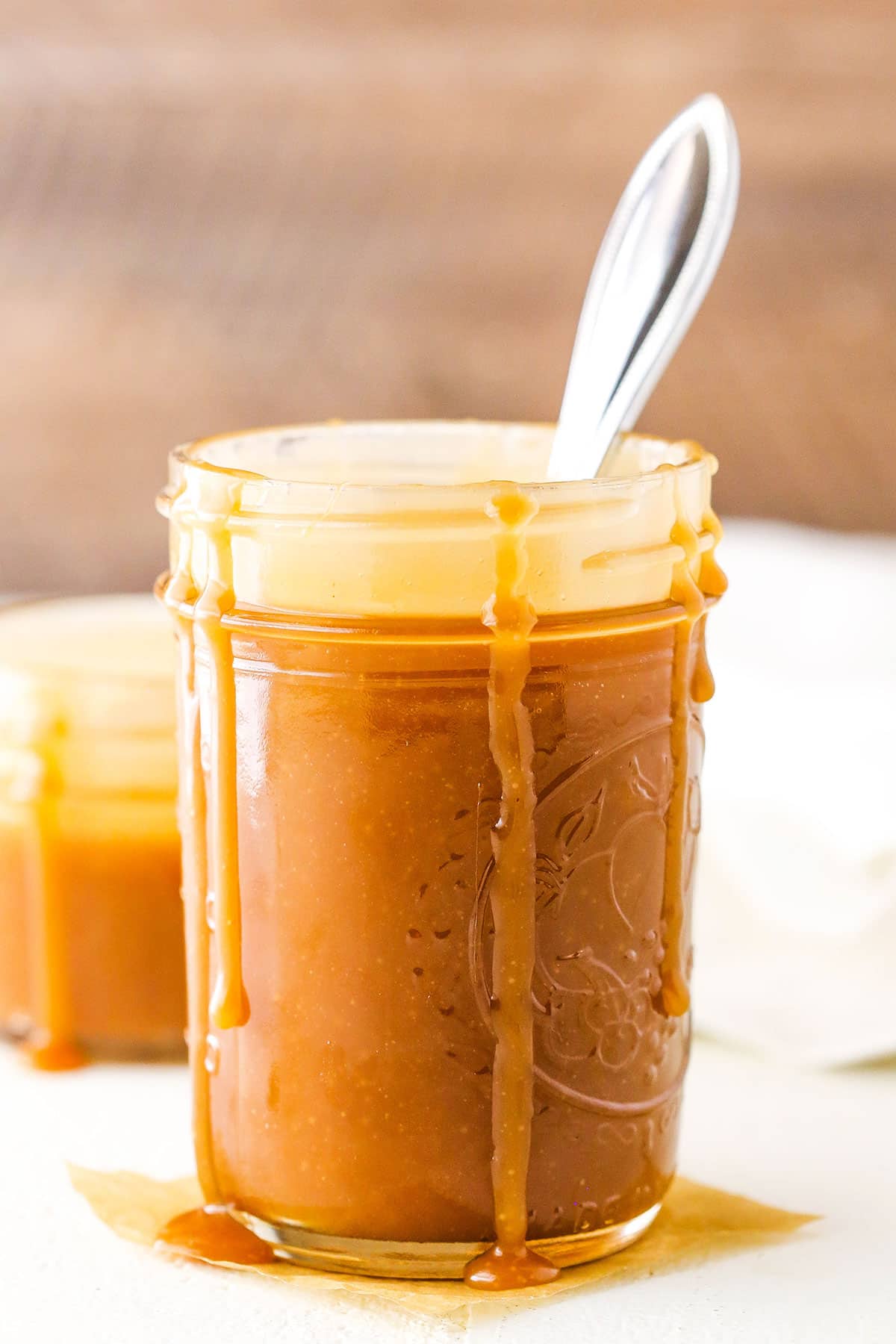 Salted Caramel Sauce in a clear glass jar with a spoon