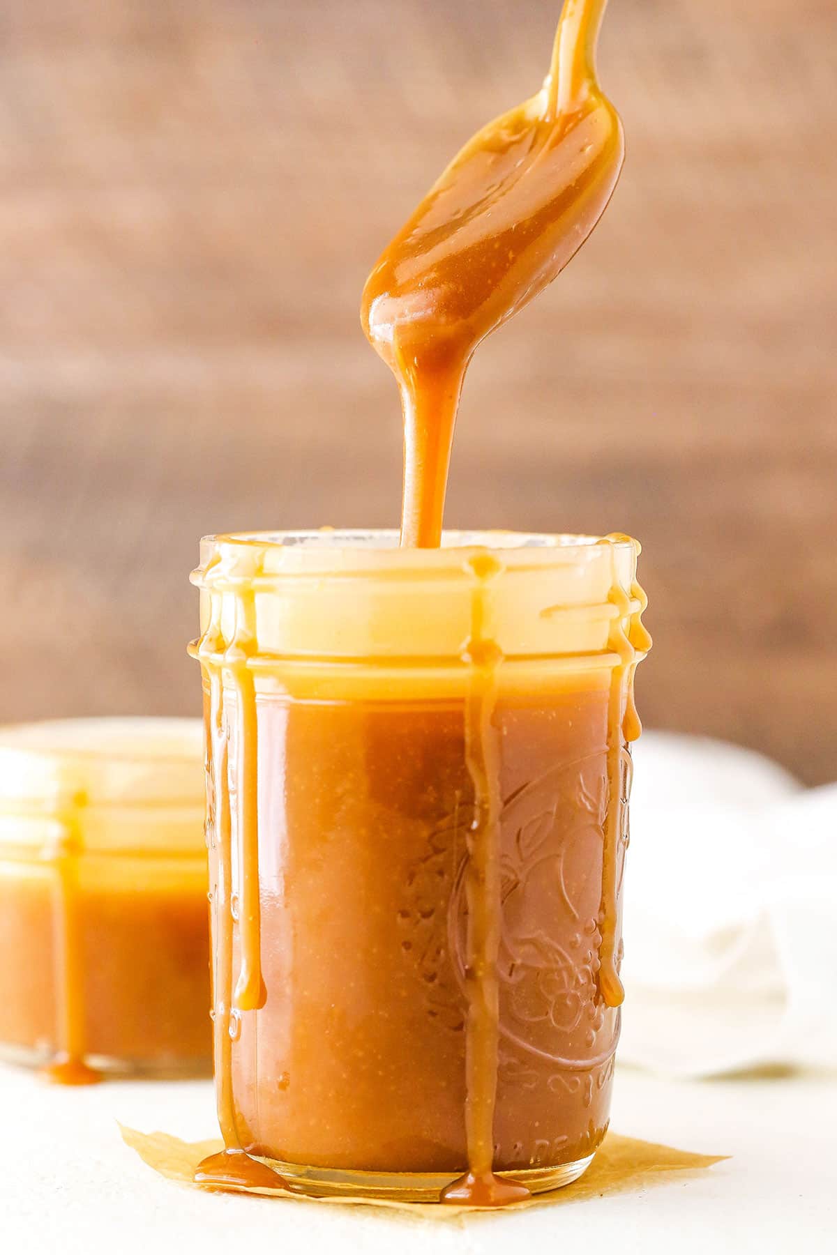 Dripping Salted Caramel Sauce off a spoon into a clear glass jar