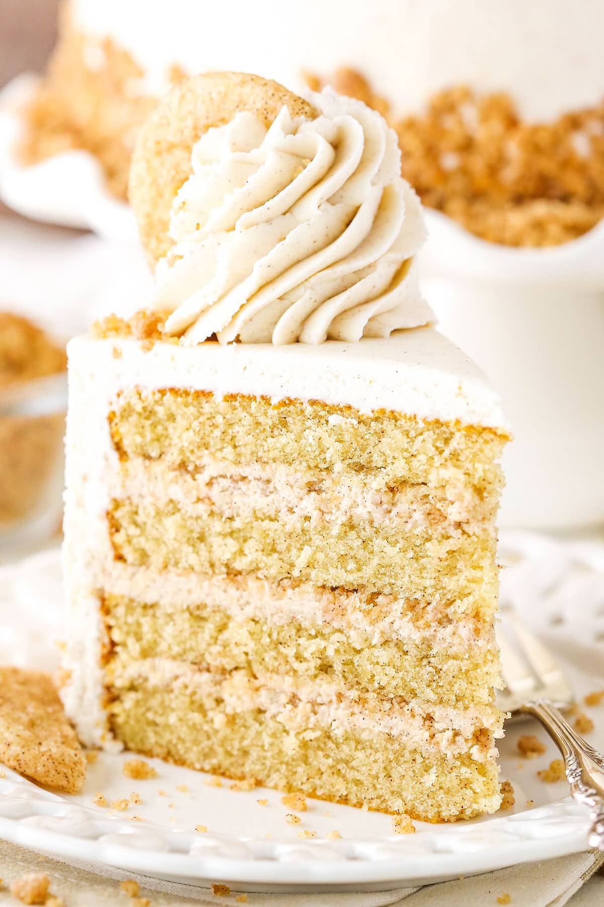 A slice of Snickerdoodle Layer Cake on a white plate with a fork