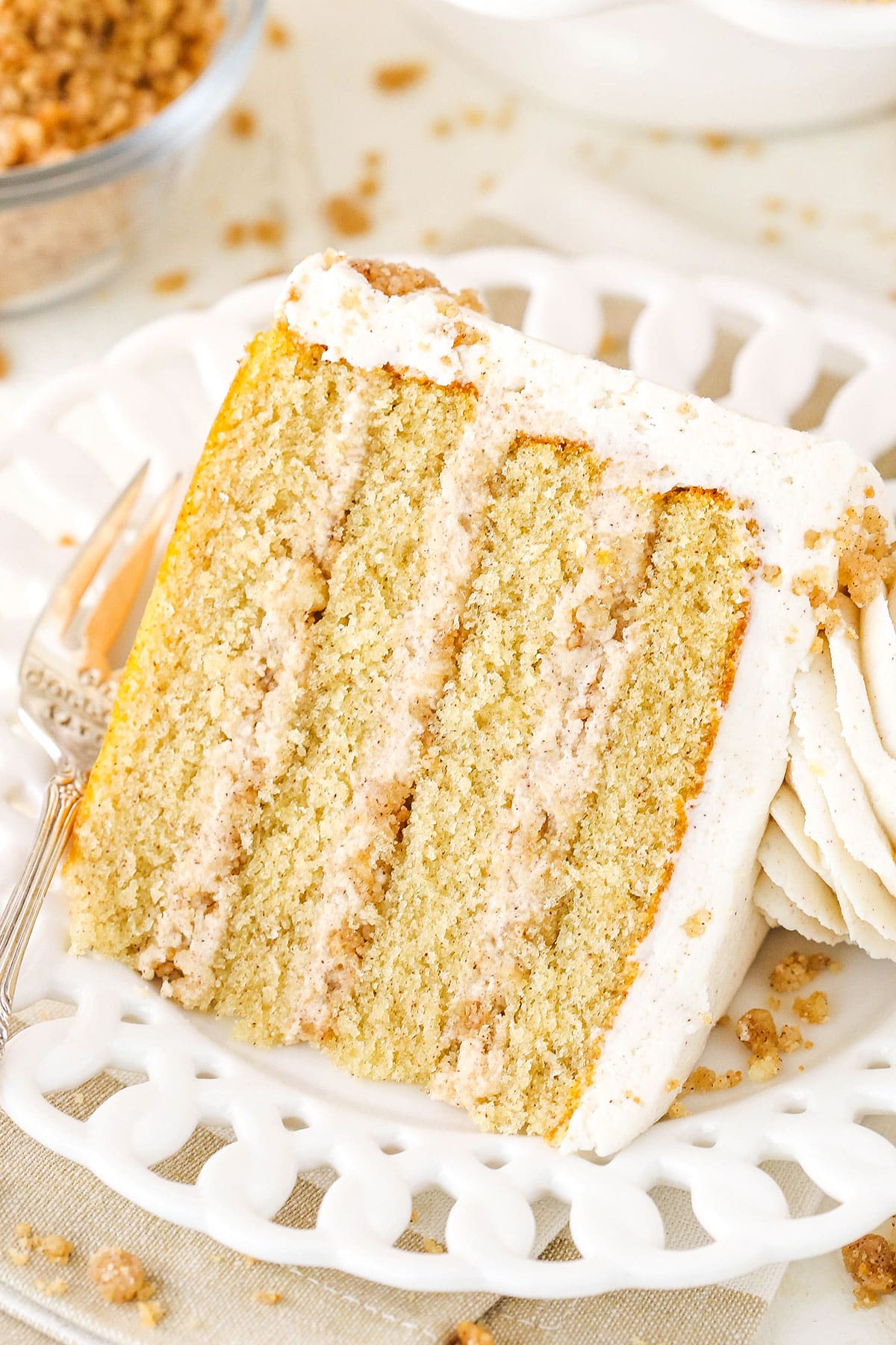 A slice of Snickerdoodle Layer Cake on it's side next to a fork on a white plate
