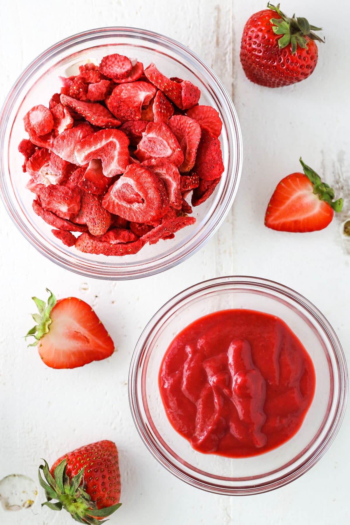 Overhead view of sliced strawberries in a clear glass bowl and pureed strawberries in a clear glass bowl