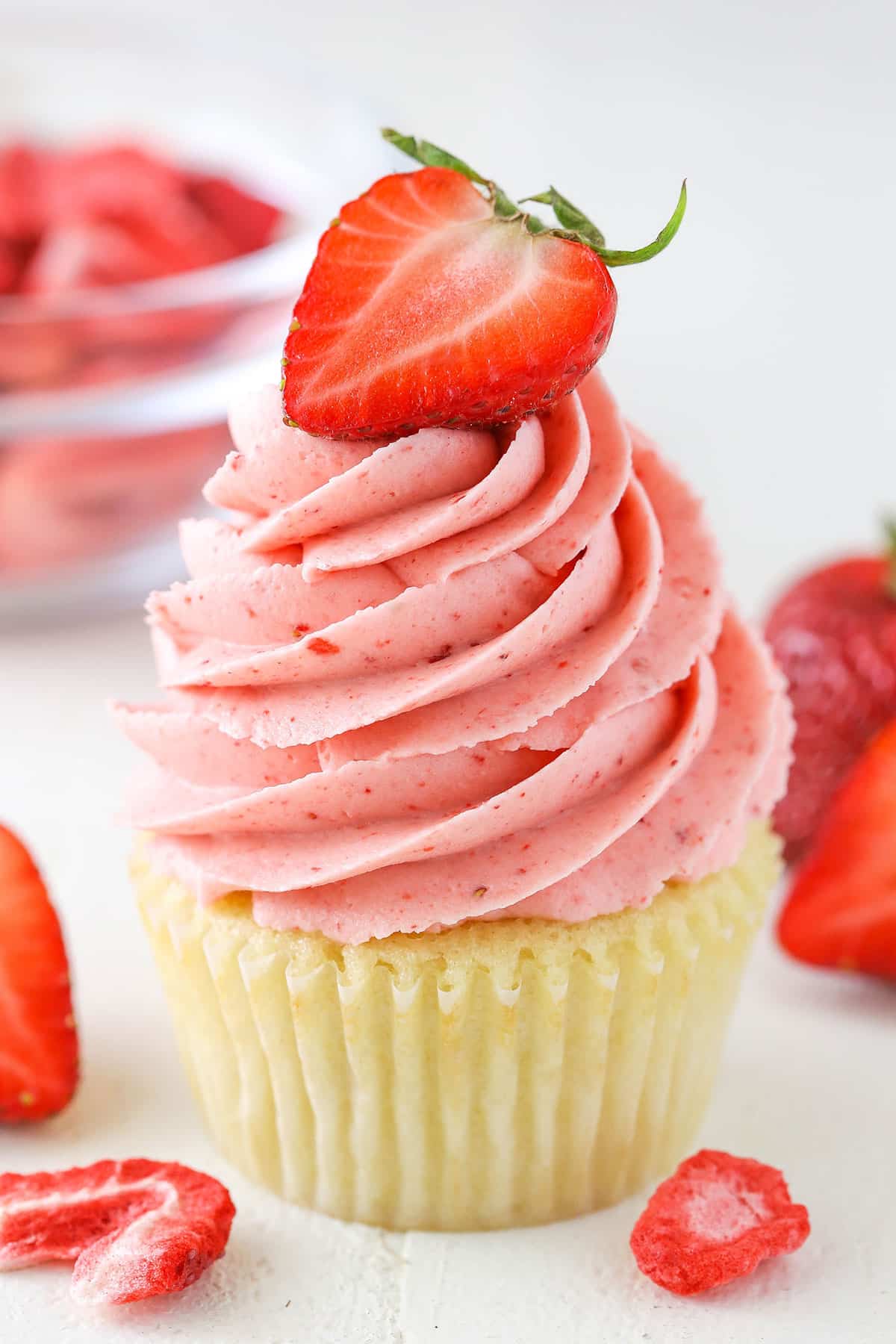 This Homemade Strawberry Frosting is the BEST you'll ever make! You can use fresh strawberries that have been reduced over the stove to increase flavor, or freeze dried strawberries! A vanilla cupcake with Homemade Strawberry Frosting piped on top