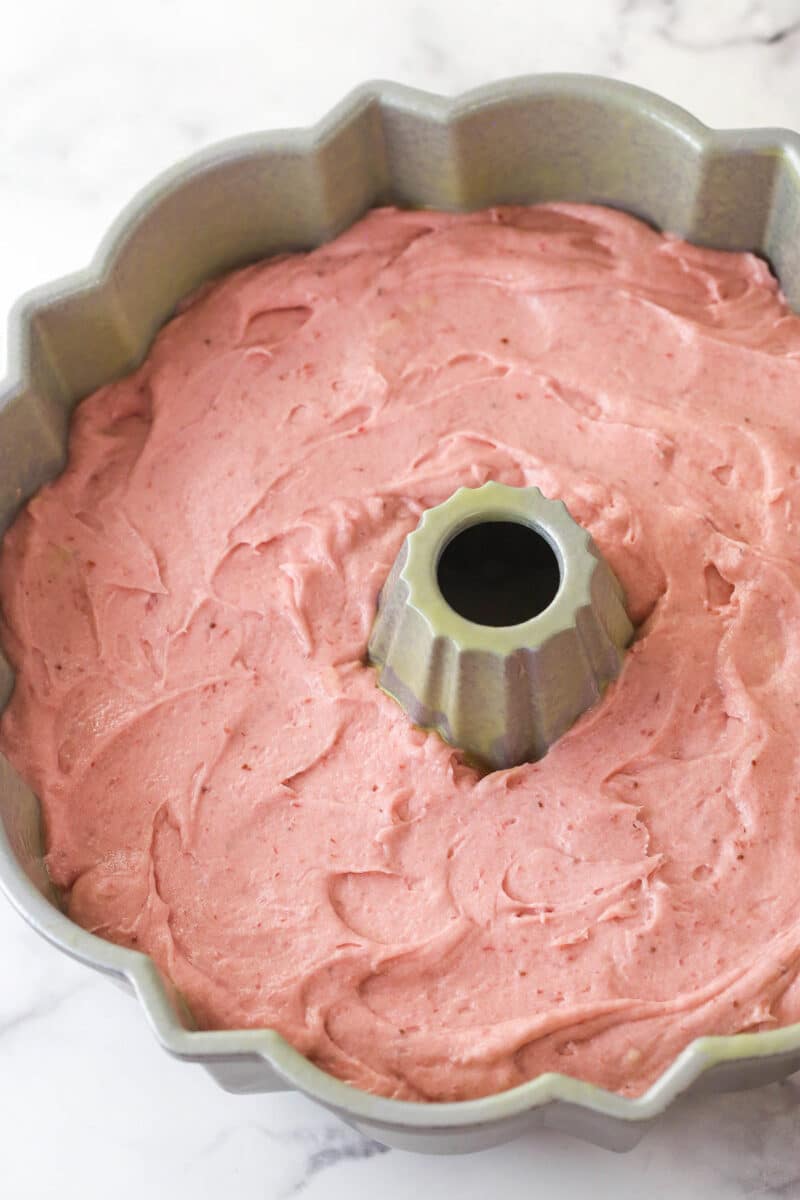 Strawberry pound cake batter spread into a bundt pan.