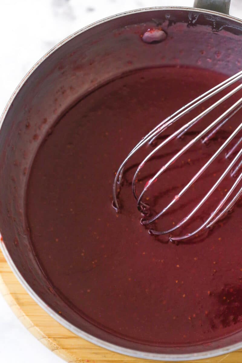 Heating ingredients for strawberry icing in a saucepan.