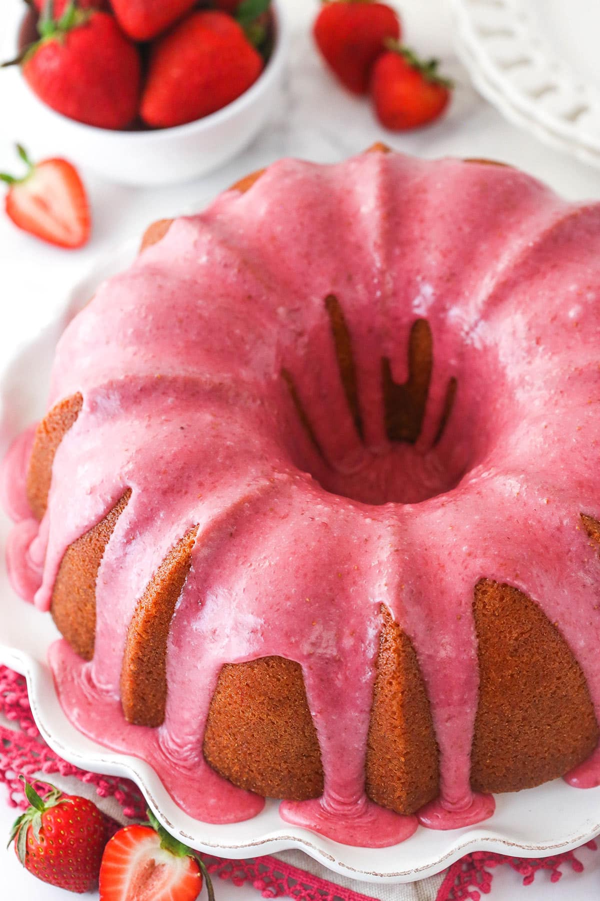 Overhead of strawberry pound cake on a serving platter surrounded by fresh strawberries.