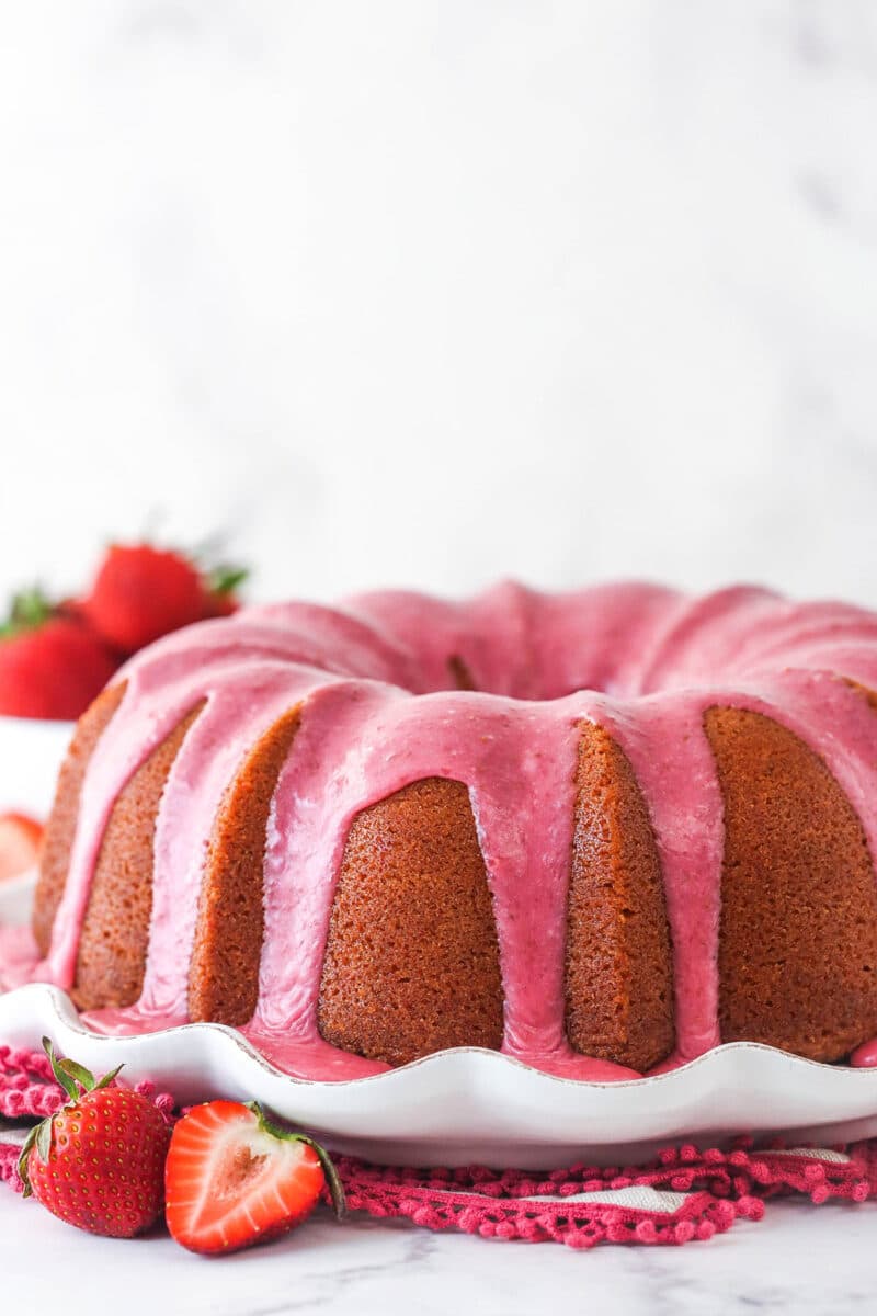 Strawberry pound cake on a serving platter surrounded by fresh strawberries.