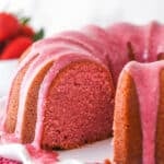 Strawberry pound cake on a serving platter with a slice taken out of it.