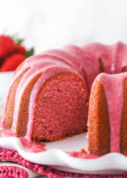 Strawberry pound cake on a serving platter with a slice taken out of it.