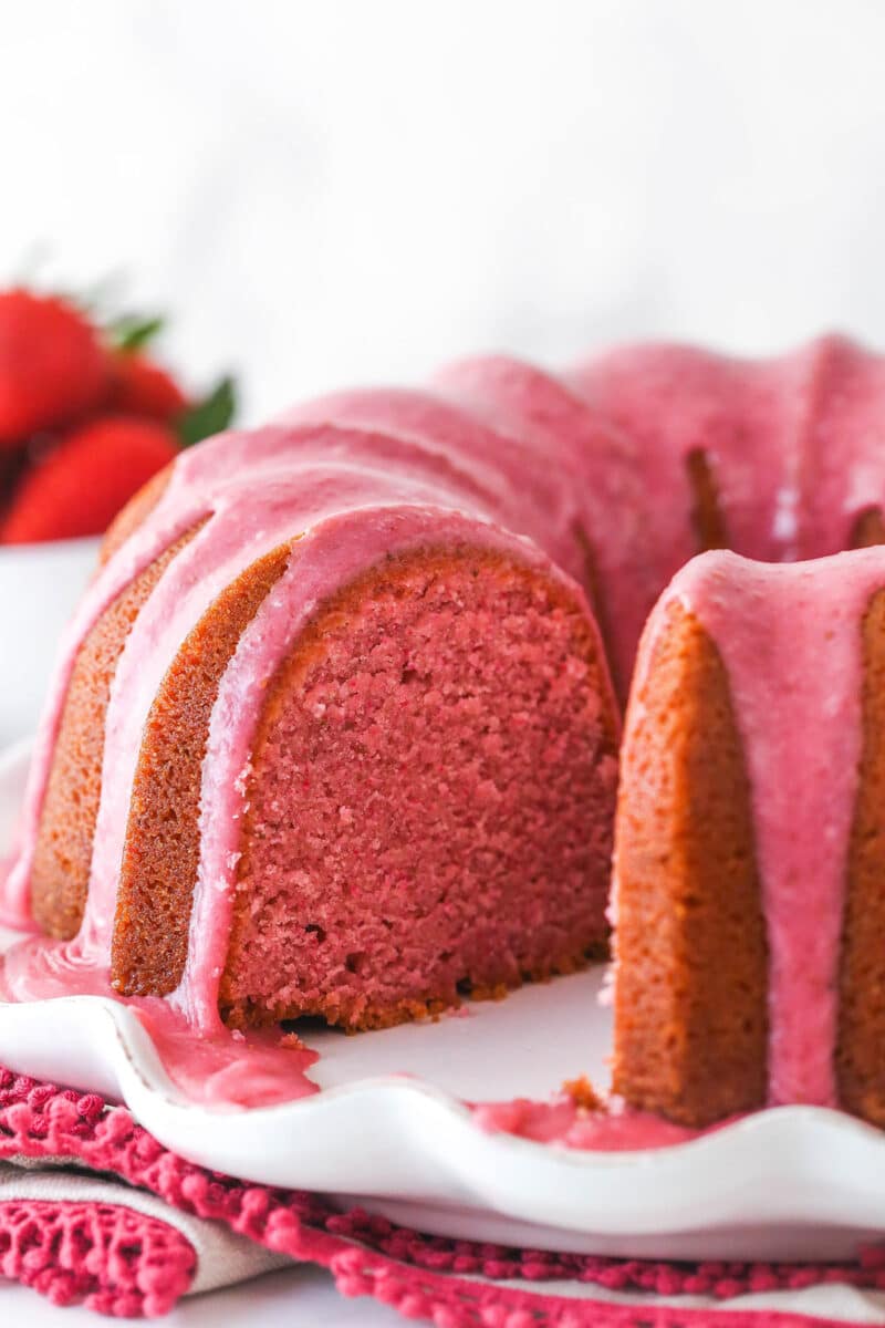 Strawberry pound cake on a serving platter with a slice taken out of it.