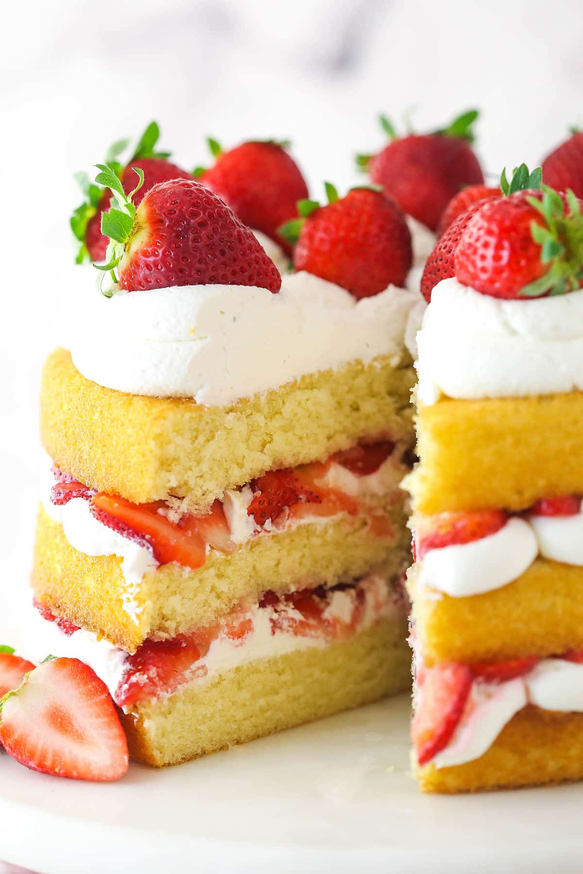 Strawberry shortcake cake with a slice taken out of it.