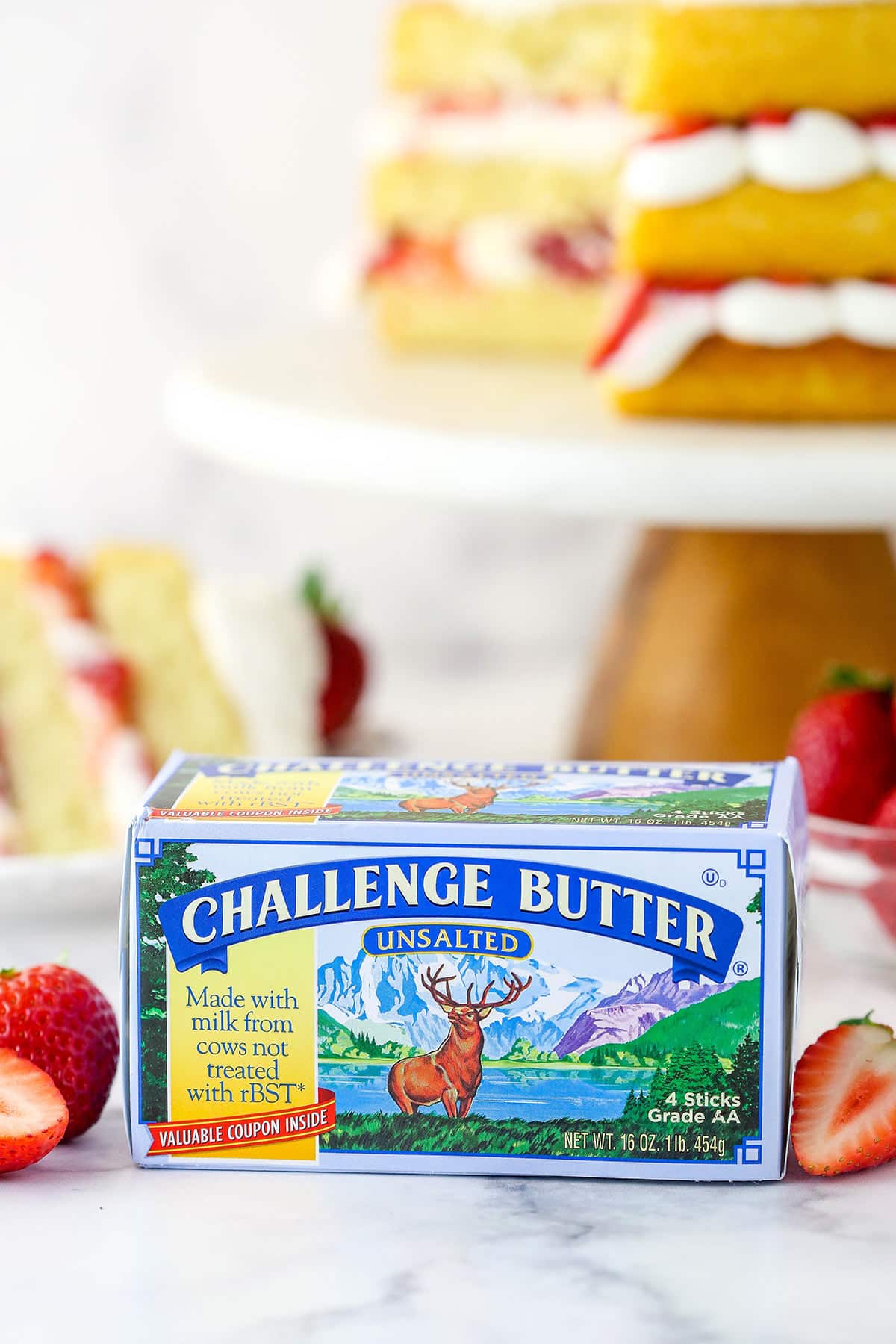Challenge butter in front of strawberry shortcake cake near fresh strawberries.