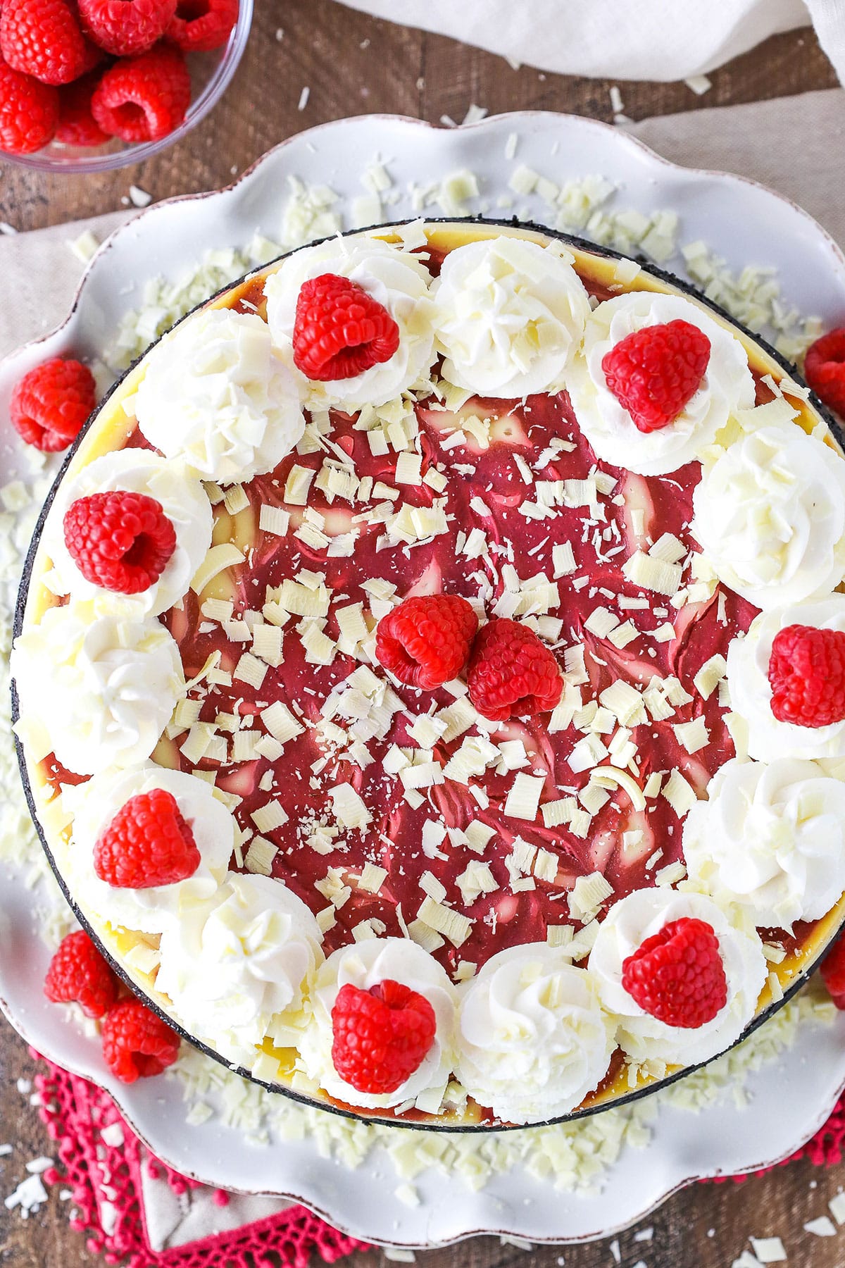 Overhead view of a White Chocolate Raspberry Cheesecake on a white cake platter