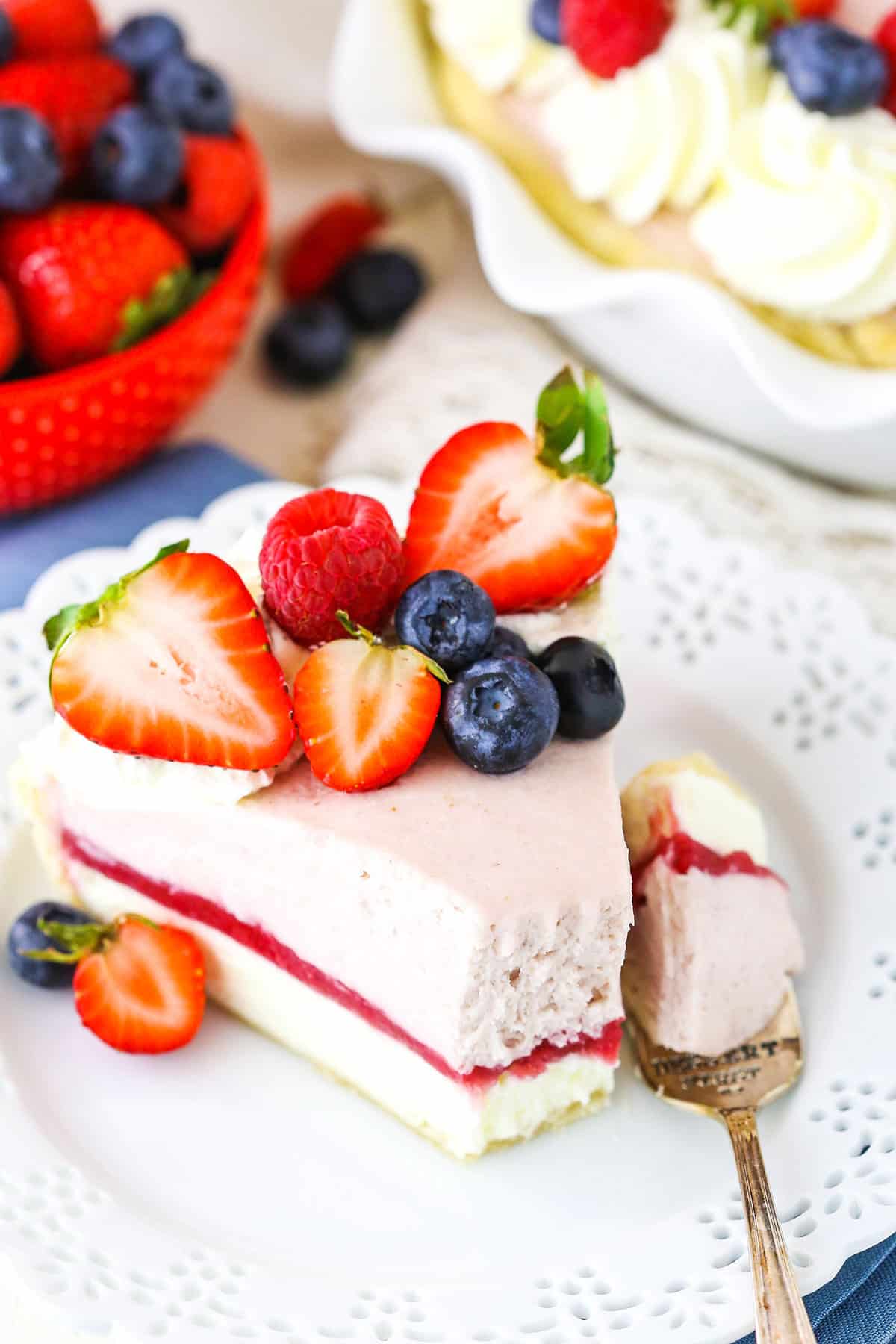 A slice of Berry Almond Cream Pie with a bite taken out next to a fork on a white plate