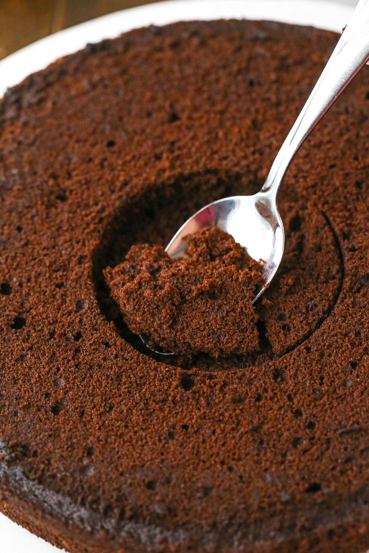 A step in making Chocolate Piñata Cake using a spoon to dig out the hole in the middle of each layer