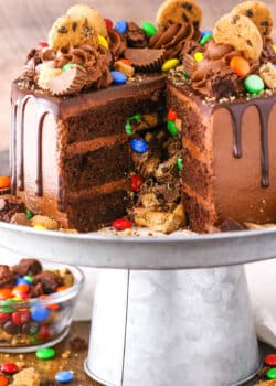 Side view of a Chocolate Piñata Cake with a slice removed on a gray cake stand