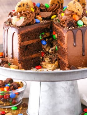 Side view of a Chocolate Piñata Cake with a slice removed on a gray cake stand