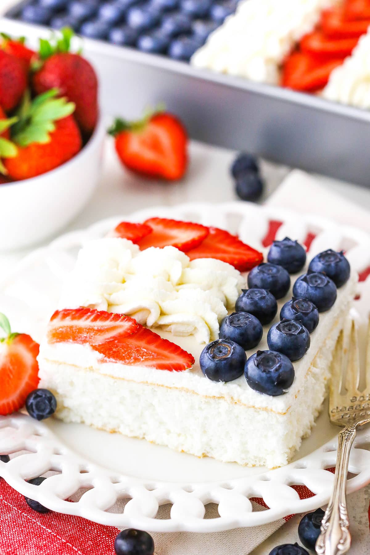 A serving of Angel Food Flag Cake next to a fork on a white plate