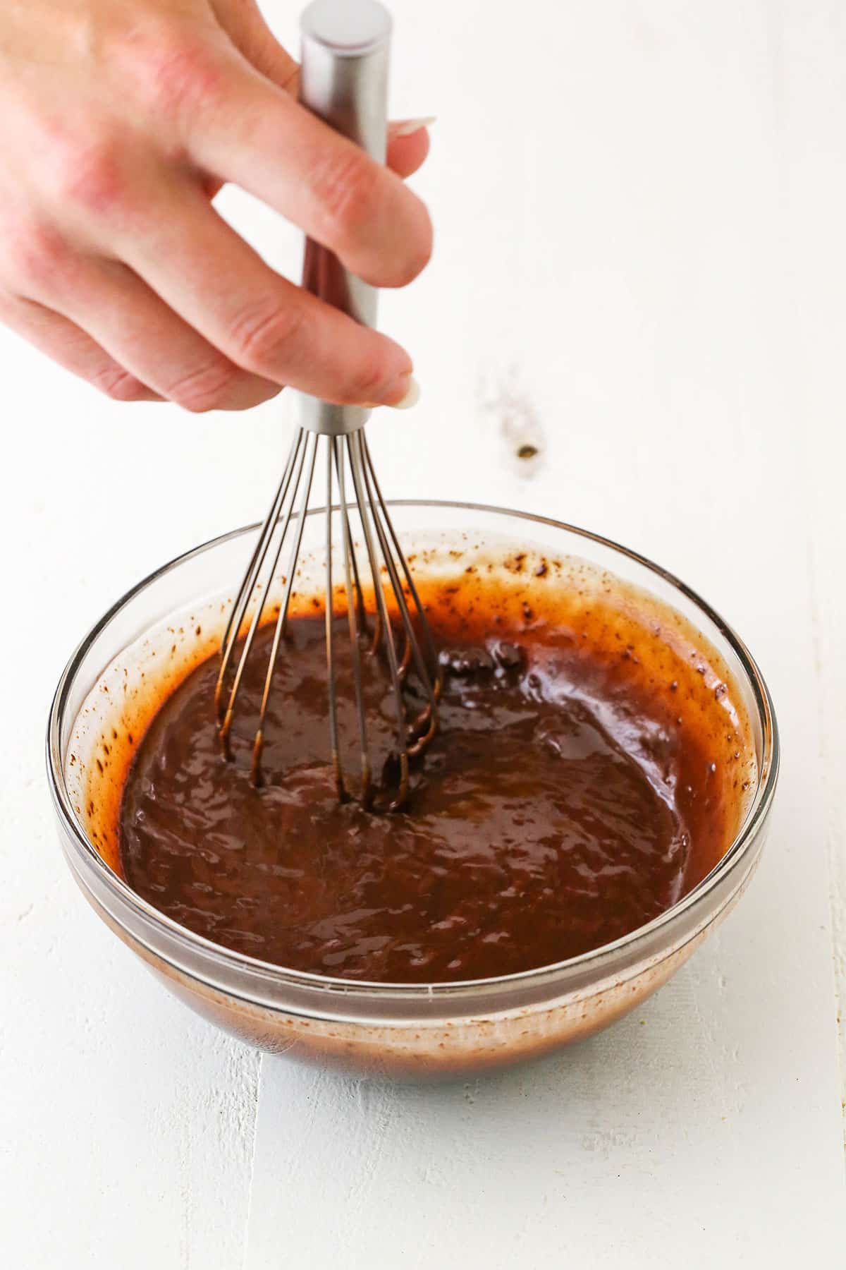 Mixing chocolate ganache using a whisk in a glass bowl