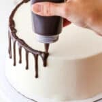 How to Make a Chocolate Drip Cake tutorial showing using a squeeze bottle to drip chocolate ganache down the sides of a cake