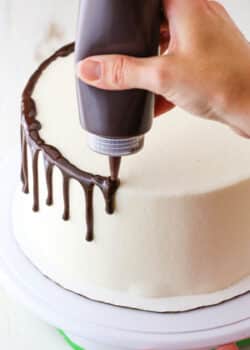 How to Make a Chocolate Drip Cake tutorial showing using a squeeze bottle to drip chocolate ganache down the sides of a cake