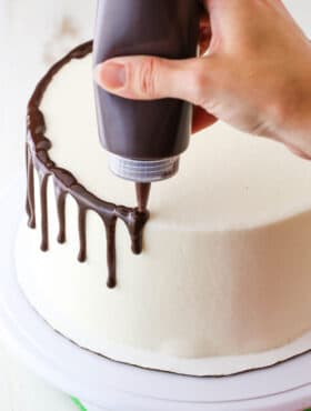 How to Make a Chocolate Drip Cake tutorial showing using a squeeze bottle to drip chocolate ganache down the sides of a cake